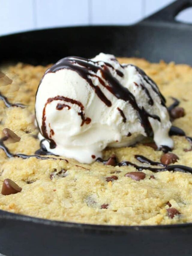 A keto-friendly skillet cookie topped with a scoop of vanilla ice cream and drizzled with chocolate syrup.