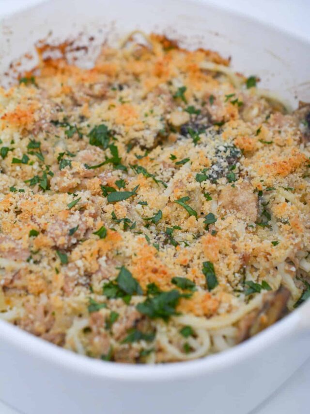 A keto-friendly baked spaghetti casserole, topped with breadcrumbs and chopped herbs, served in a white dish.