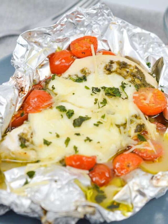 Caprese-inspired chicken breast topped with melted cheese, chopped herbs, and cherry tomatoes, all grilled to perfection and served in aluminum foil. Perfect for a delicious keto-friendly meal!
