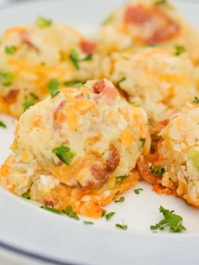 Creamy cheese and bacon potato salad garnished with chopped parsley, served on a white plate.