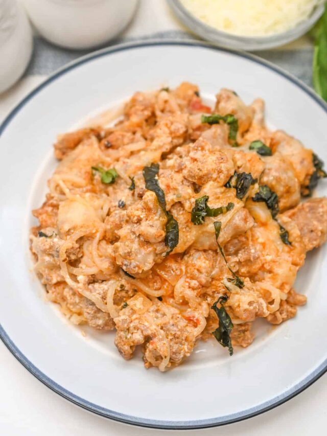 A plate of spaghetti squash lasagna with a creamy tomato sauce, ground meat, and fresh basil leaves, served on a white dish—perfect for those on a keto diet.