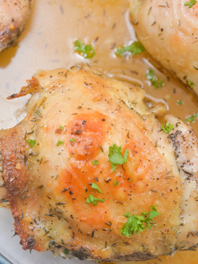 Close-up of a baked chicken thigh garnished with chopped parsley and seasoning, sitting in a light brown sauce. The skin is golden and slightly crispy, making it perfect for delectable low carb meal ideas.