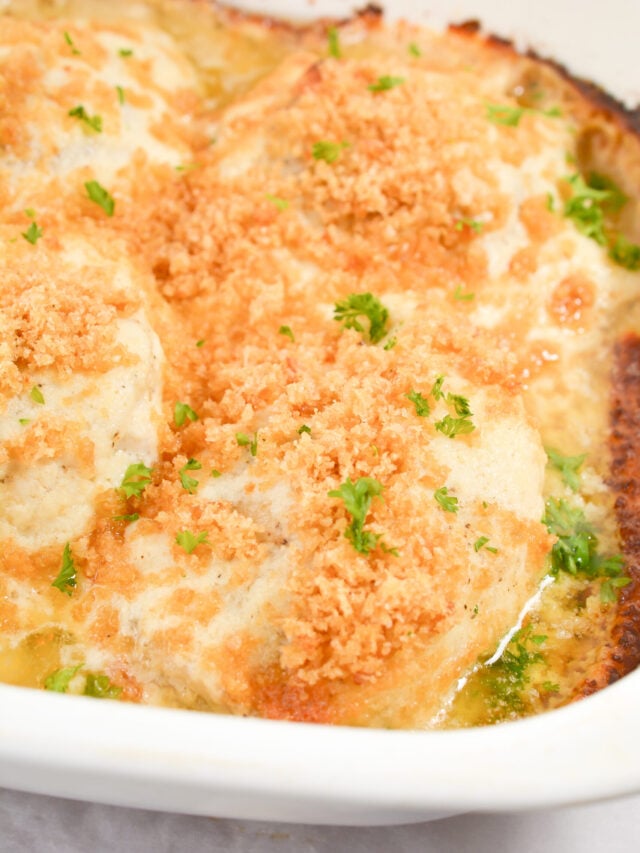A close-up of a baked dish featuring chicken thighs topped with a crispy breadcrumb and herb crust in a white casserole dish, perfect for a keto-friendly meal.