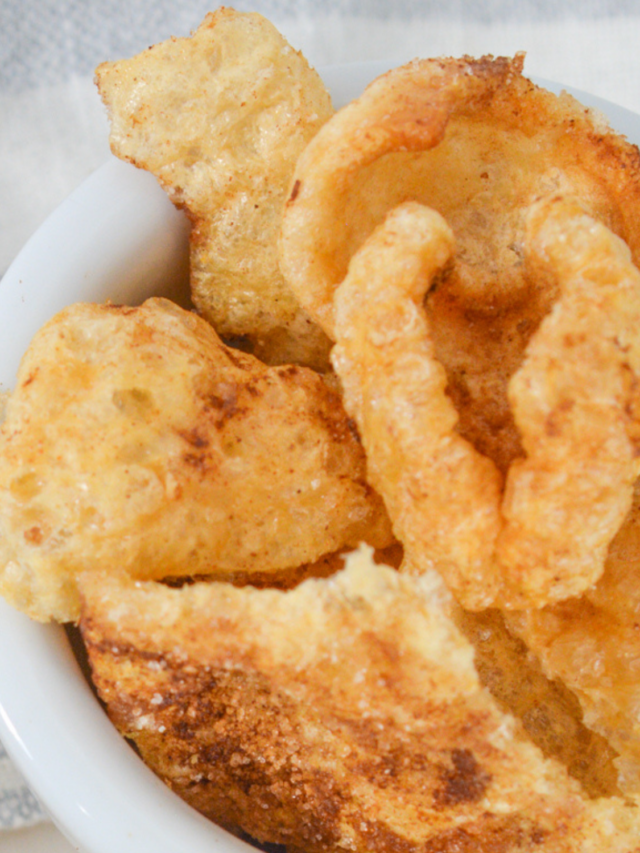 A close-up of a white bowl filled with crispy, golden-brown pork rinds, dusted with a hint of cinnamon sugar.